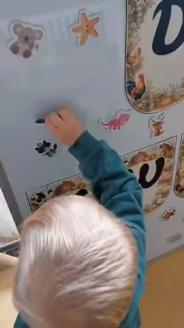 Dziecko przy tablicy z napisem „Dzień Zwierząt”